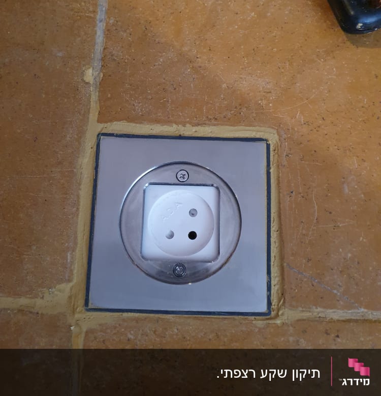 שקע חשמלי מותקן בקיר אריחים חומים